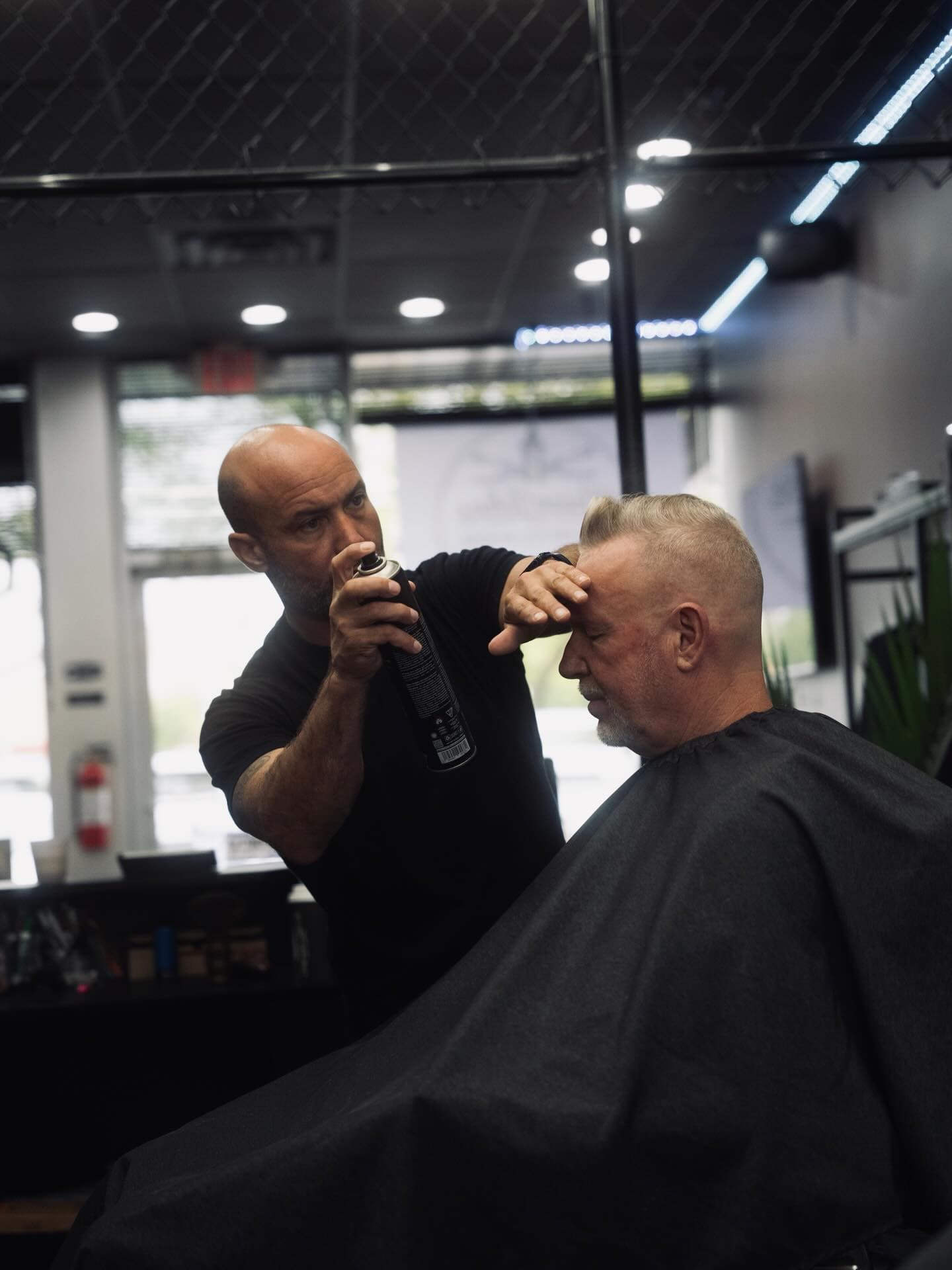 Barber applying finishing spray during a haircut at The Men's Room